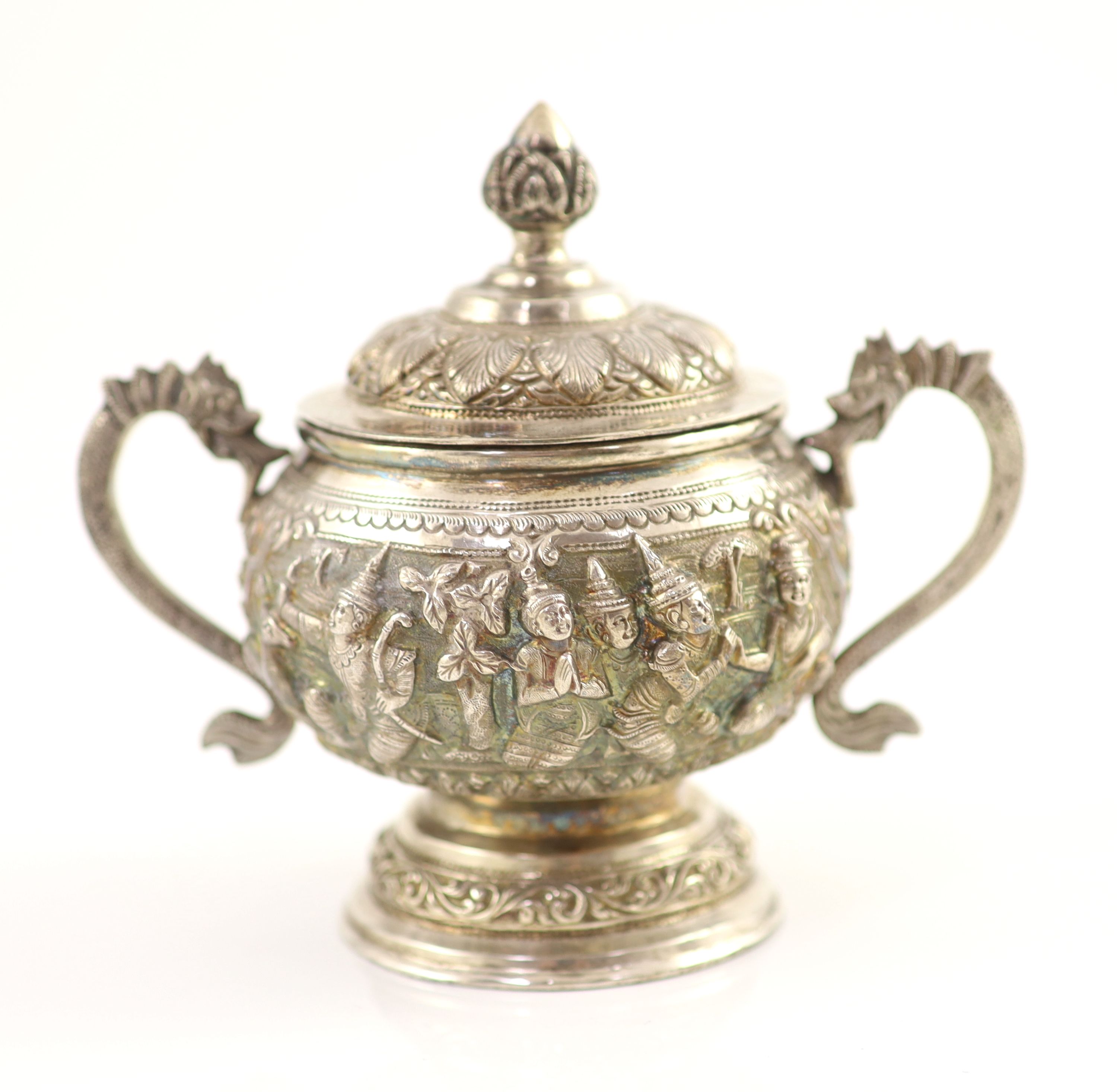 An impressive Burmese Sterling silver (950) three-piece tea service, with tray, cast with figures, teapot with cockerel spout and figural handle